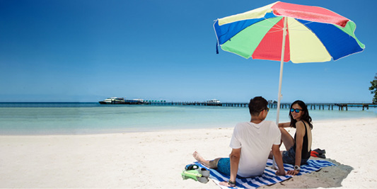Cairns Tours. Great Barrier Reef. Island visit. Couple sitting on the beach at Green Island